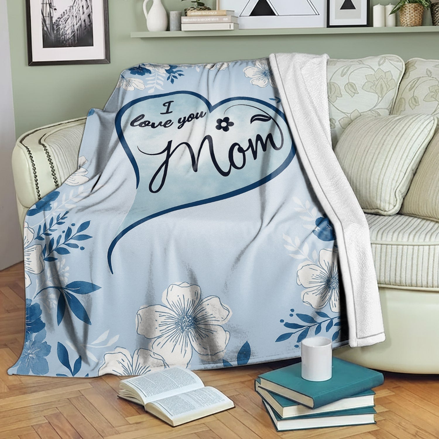 Blue floral mom blanket with heart design draped over a cozy green sofa — Discover heartfelt personal gifts at HerTender.com