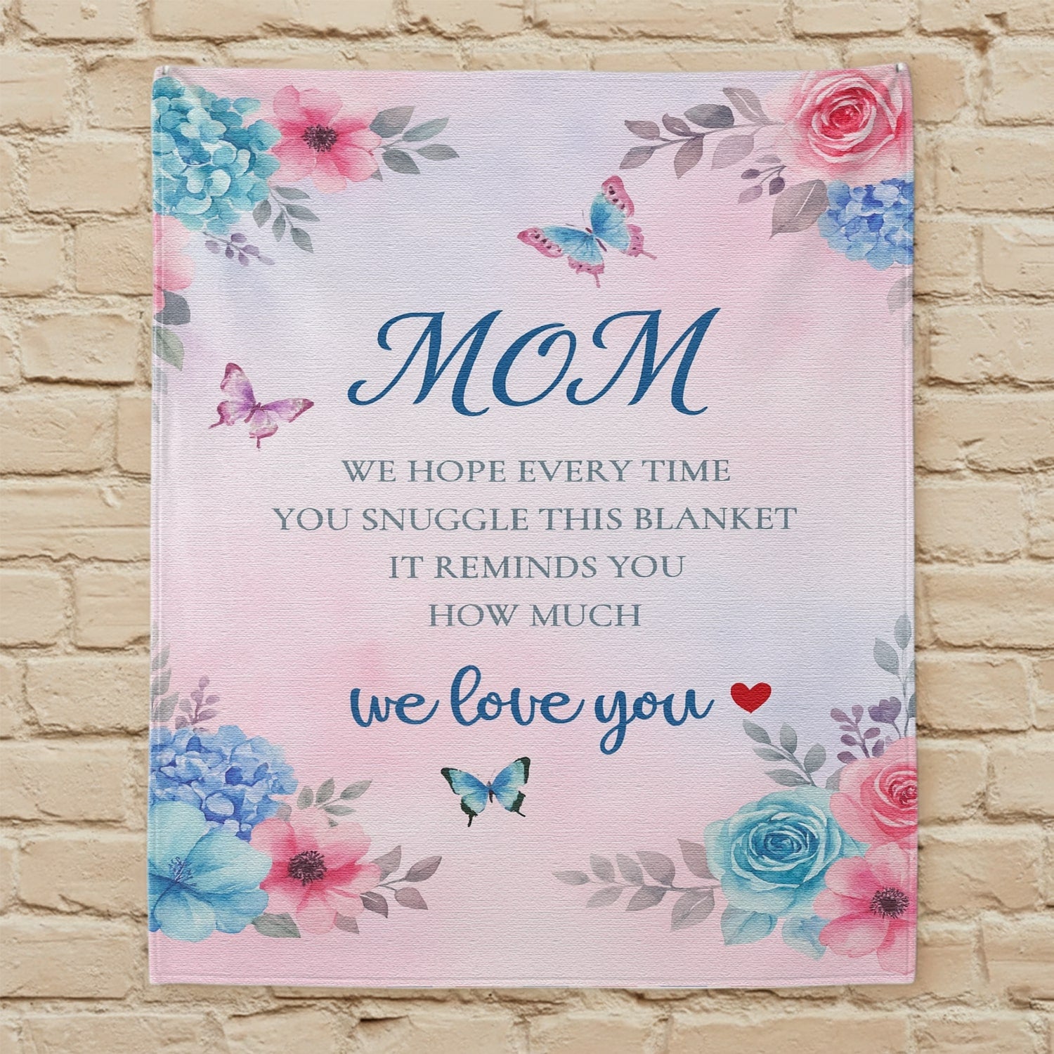 Pastel floral mom blanket with butterflies and loving message displayed on a beige wall — Discover heartfelt personal gifts at HerTender.com