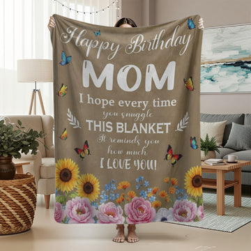 Woman holding a floral birthday blanket for mom with butterflies and heartfelt message, symbolizing personalized gifts — Discover heartfelt personalized gifts at HerTender.com.