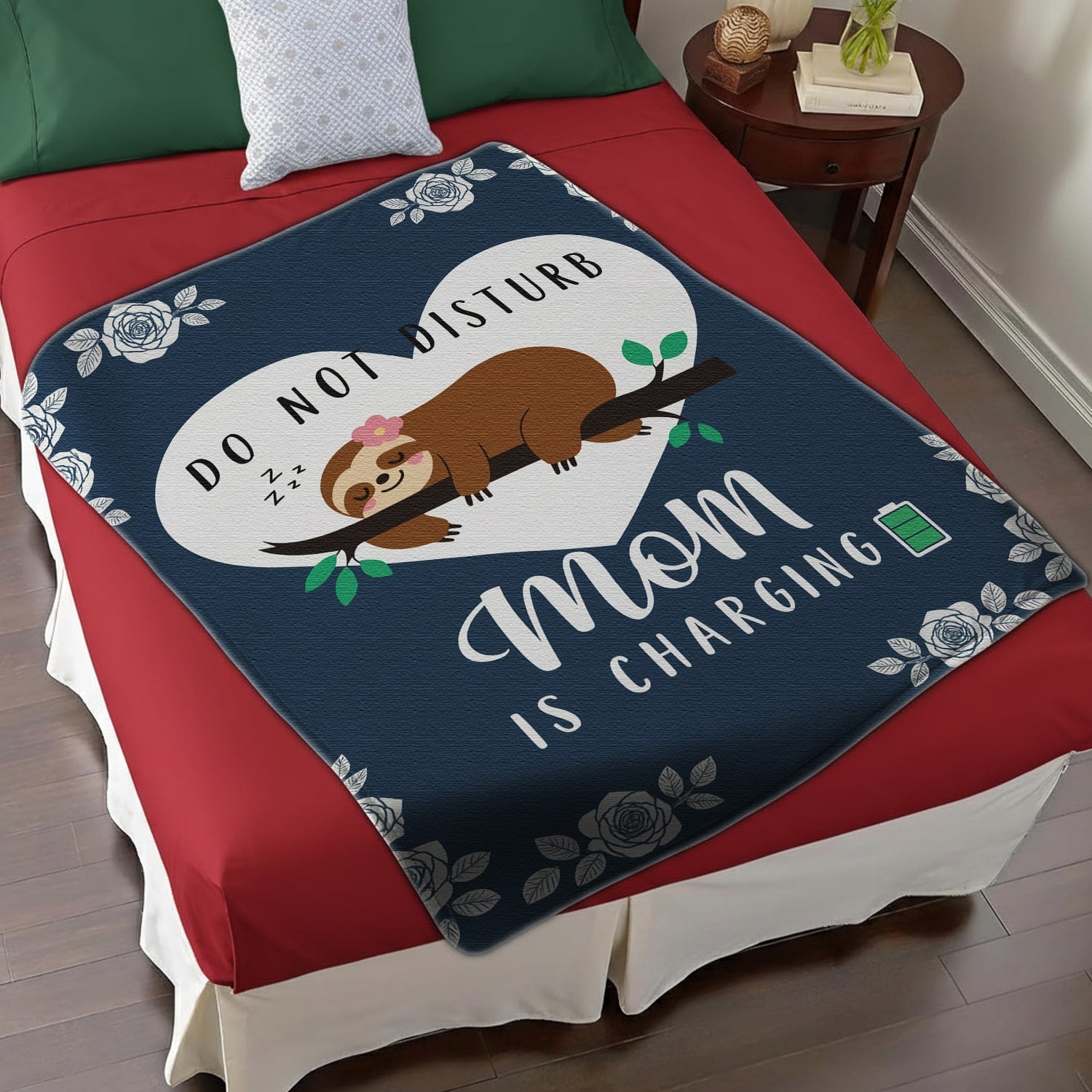 Do Not Disturb Mom Is Charging blanket with a cute sloth and floral accents on a red bed, symbolizing cozy personalized gifts — Discover heartfelt personalized gifts at HerTender.com.