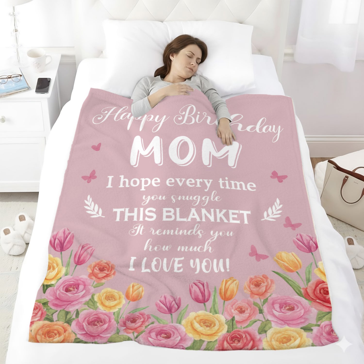 Woman sleeping under a pink “Happy Birthday Mom” floral blanket — Surprise her with a soft, heartfelt personalized gift from HerTender.com.
