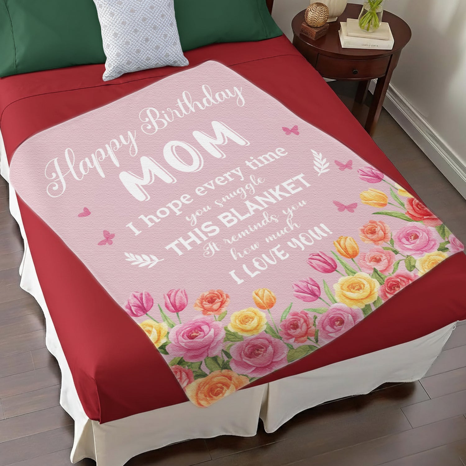Pink floral “Happy Birthday Mom” blanket on a red bed — Give mom a heartfelt surprise with meaningful personalized gifts from HerTender.com.