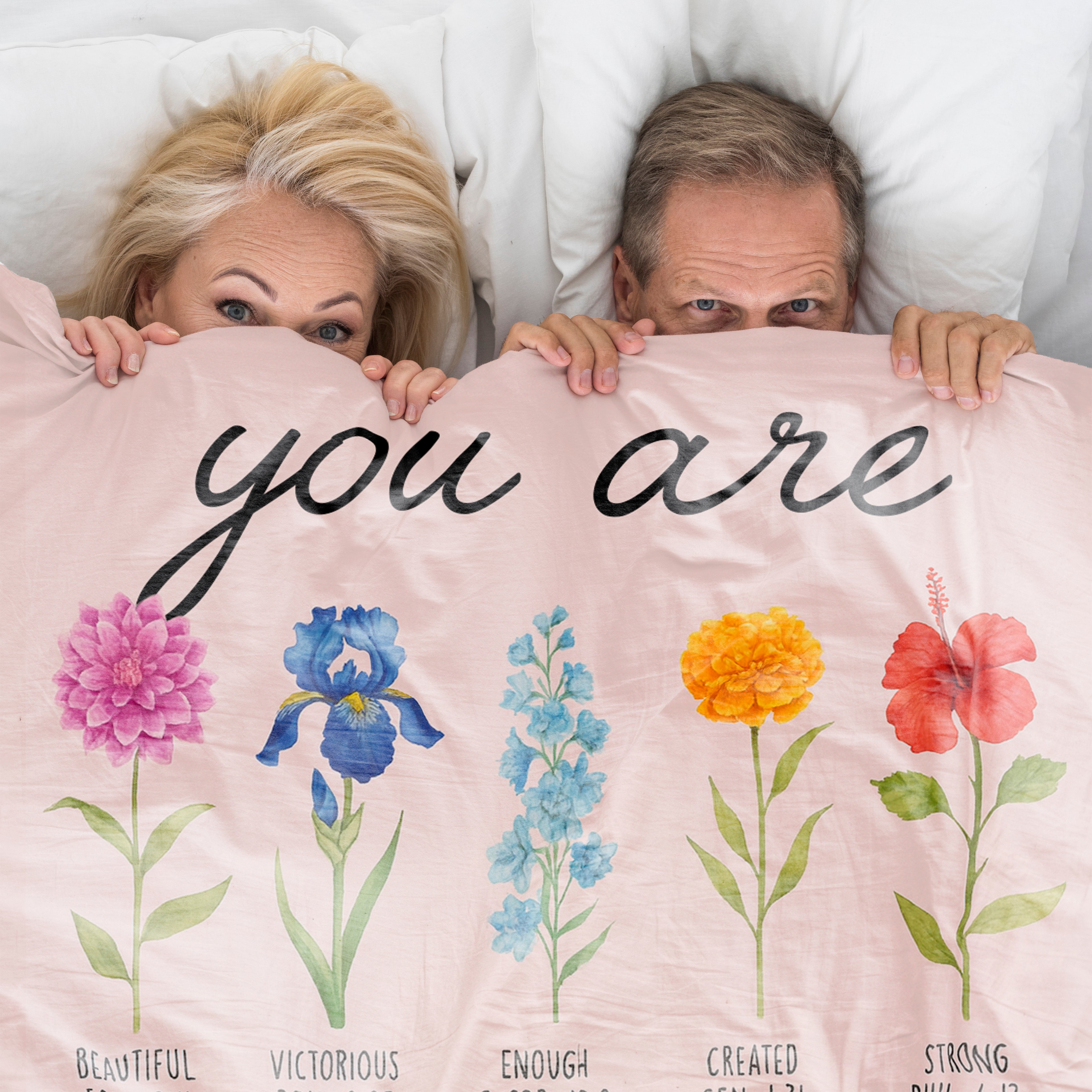Couple smiling under a floral blanket with the words “You Are” and Bible verse affirmations, symbolizing faith-inspired personalized gifts — Discover heartfelt personalized gifts at HerTender.com.