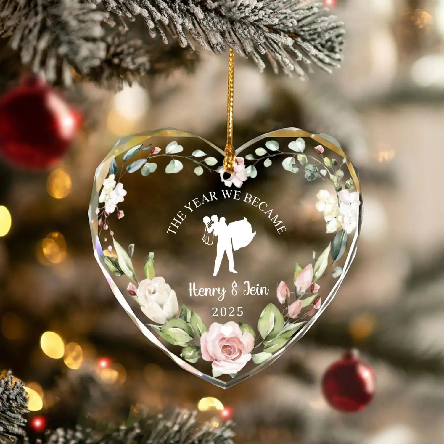 Heart-shaped personalized glass ornament with floral design and bride-and-groom silhouette hanging on a Christmas tree — Discover romantic personalized gifts that celebrate your love at Hertender.com.