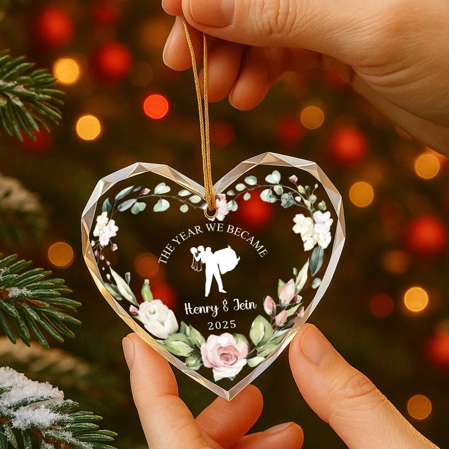 Hands holding heart-shaped personalized glass ornament with floral design and bride-and-groom silhouette — Discover romantic personalized gifts that celebrate love at Hertender.com.