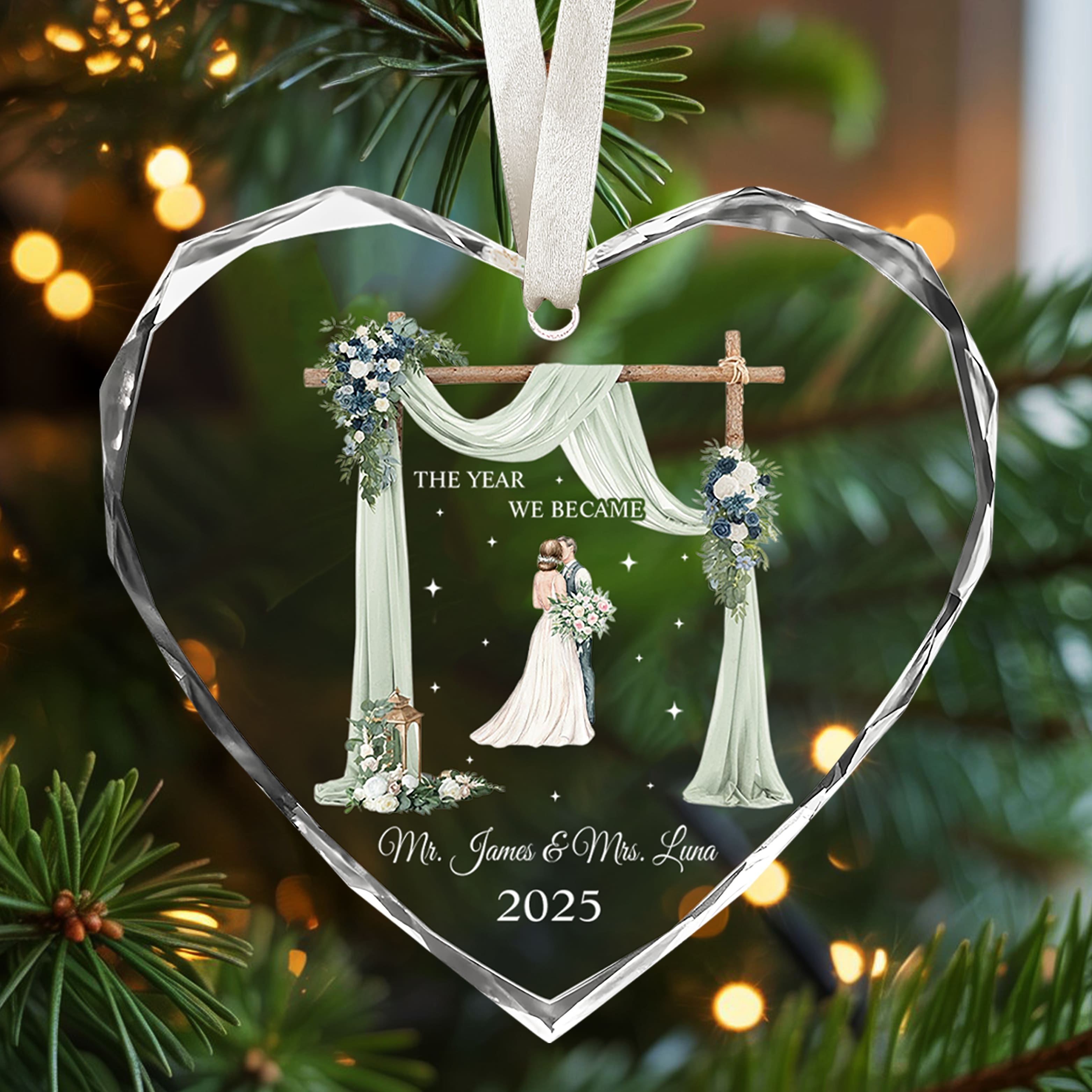 Heart-shaped glass ornament engraved with bride and groom illustration and “The Year We Became Mr. & Mrs.” glowing on a Christmas tree — Celebrate love with meaningful personalized Christmas gifts from Hertender.com.