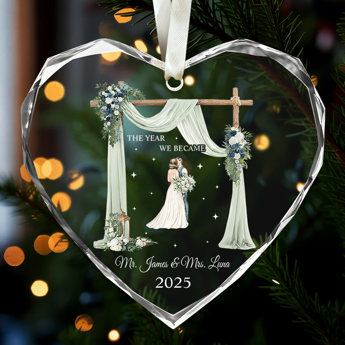 Heart-shaped glass ornament engraved with bride and groom illustration and “The Year We Became Mr. & Mrs.” glowing on a Christmas tree — Celebrate love with meaningful personalized Christmas gifts from Hertender.com.