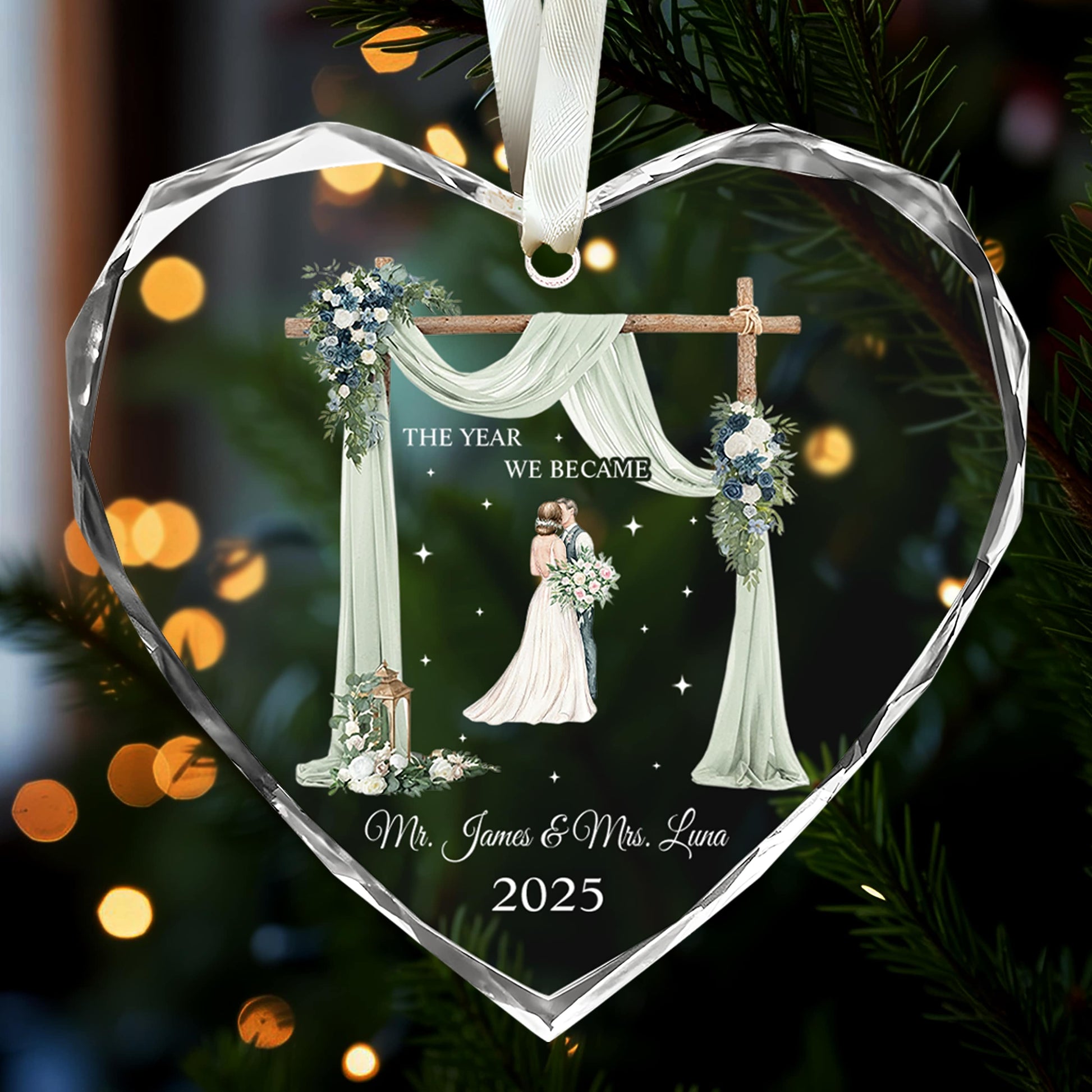 Heart-shaped glass ornament engraved with bride and groom illustration and “The Year We Became Mr. & Mrs.” glowing on a Christmas tree — Celebrate love with meaningful personalized Christmas gifts from Hertender.com.