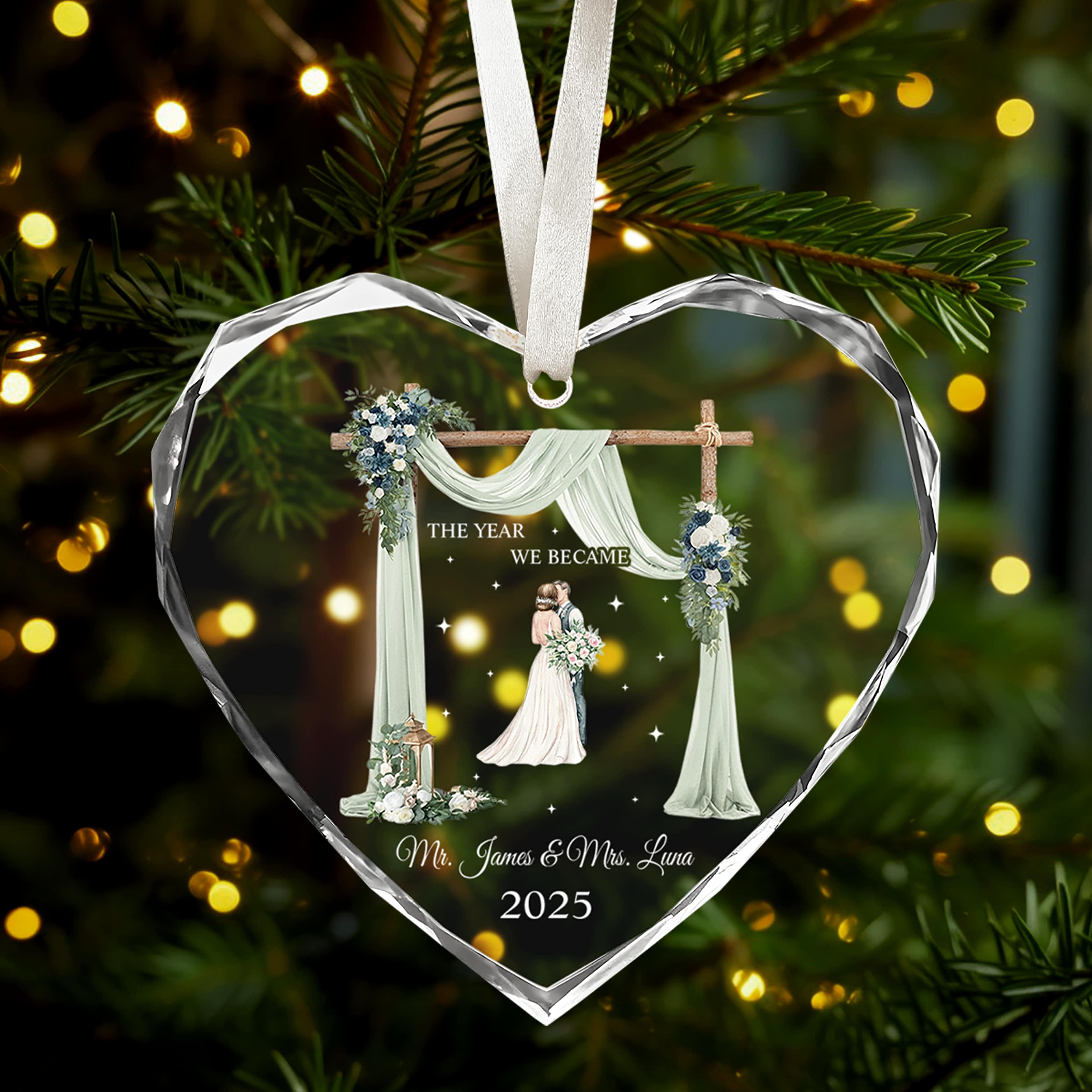 Heart-shaped glass ornament engraved with bride and groom illustration and “The Year We Became Mr. & Mrs.” glowing on a Christmas tree — Celebrate love with meaningful personalized Christmas gifts from Hertender.com.