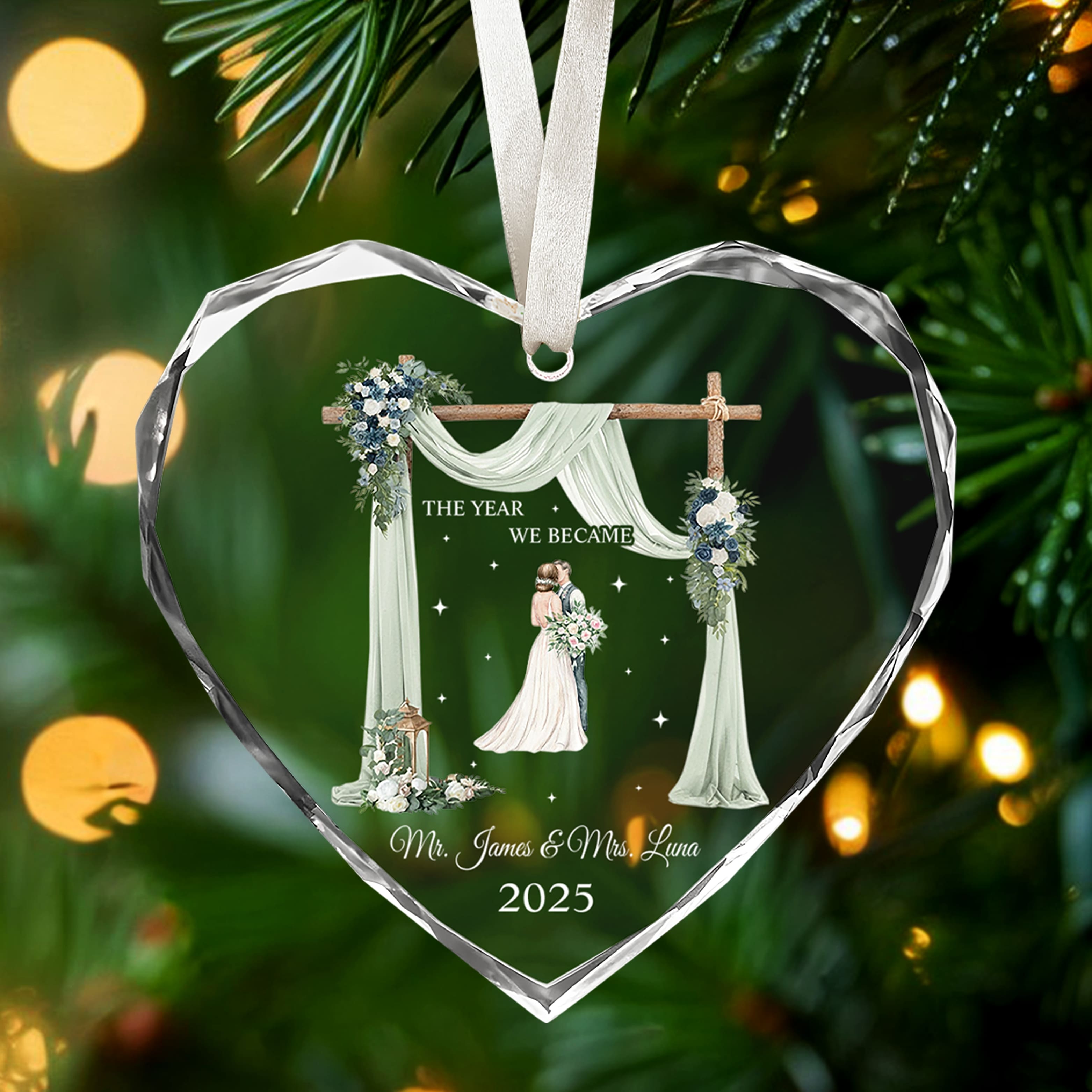 Heart-shaped glass ornament engraved with bride and groom illustration and “The Year We Became Mr. & Mrs.” glowing on a Christmas tree — Celebrate love with meaningful personalized Christmas gifts from Hertender.com.