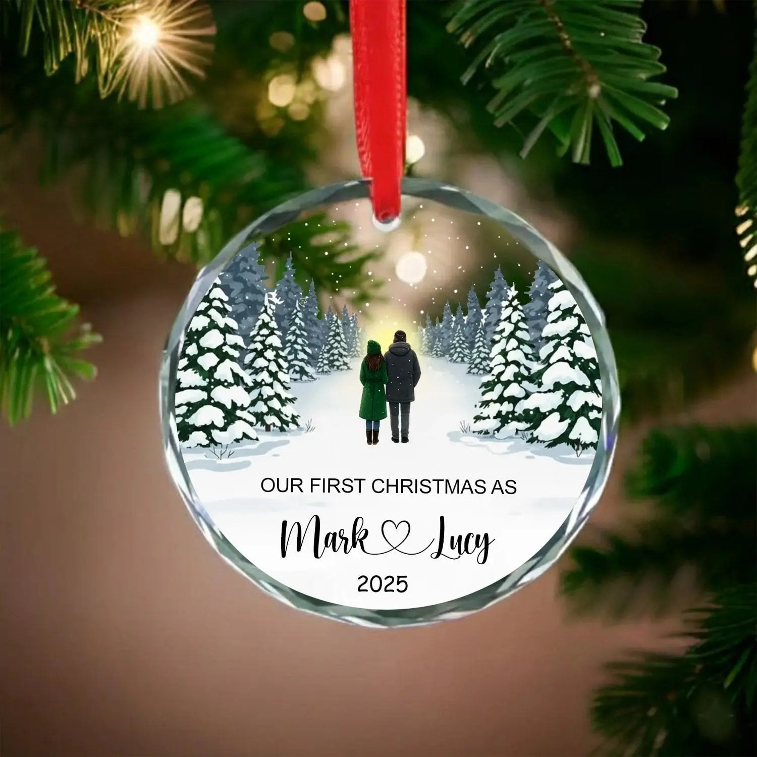 Round personalized glass ornament with snowy forest couple design and text “Our First Christmas As Mark and Lucy 2025” — A heartfelt keepsake to celebrate your first Christmas together from Hertender.com.
