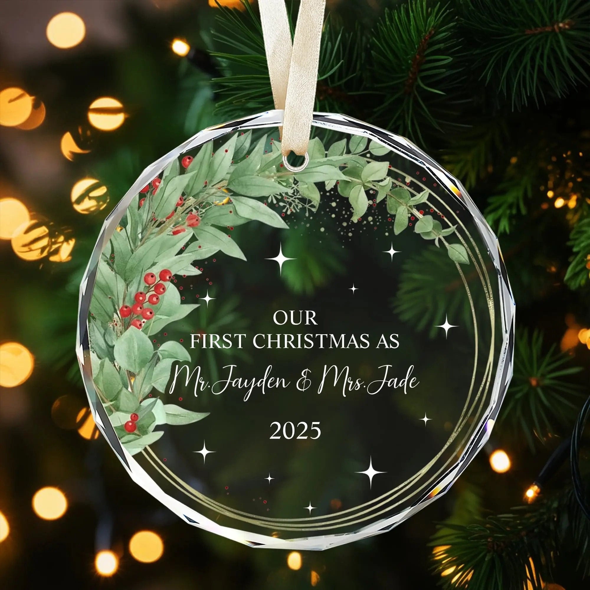 Personalized glass Christmas ornament with greenery and red berry wreath for a couple’s first Christmas — Celebrate love with meaningful personalized gifts from Hertender.com.